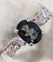 Top view showing oval dark blue center stone and CZ-set shoulders