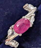 Top view of silver ring showing oval ruby and marquise accent stones