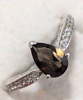 Angled view of sterling silver ring highlighting pear smoky quartz and CZ shoulder stones
