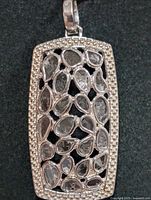 front view of rectangular silver pendant showing diamond slices and pavé border