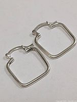 Square silver-tone hoop earrings laid flat showing front view