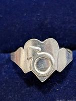 Front view showing raised circle and arrow motif on silver ring