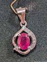 Front view of silver pendant showing ruby and accent stones