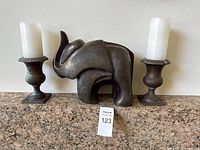 Elephant sculpture centered between two candlesticks