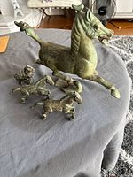 All four bronze horse figurines on table showing relative sizes