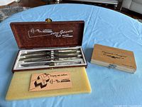 Open faux-leather case showing six steak knives; closed wooden case beside it