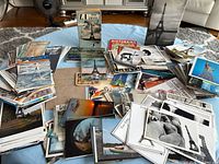 Wide view of entire lot spread on table showing large quantity of postcards and small booklets