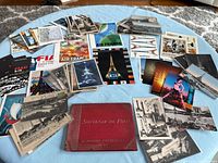 Wide view of assorted postcards spread on table around red souvenir booklet