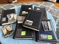 Six albums with stacks of loose postcards, sticky notes indicating 1900s era