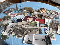 Overview of entire lot showing spread of postcards, souvenir folders and two Eiffel Tower figurines
