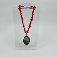 Full view of coral bead necklace hanging, pendant visible