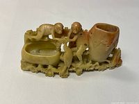 front view of carved stone statue with two monkeys, pot and dish