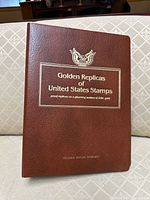 Front of brown binder titled Golden Replicas of United States Stamps