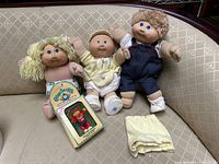 Three dolls, boxed figure and shorts on couch