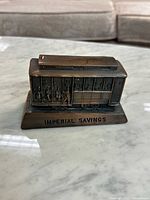 Front and side view of die cast cable car bank showing Imperial Savings inscription