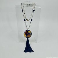 Full view of quartz bead necklace with cloisonne pendant and tassel on stand