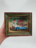 Front view showing framed diorama with toy car and illustrated background