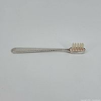 Full view of sterling silver child’s toothbrush lying flat