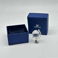 Mini crystal globe figurine beside open blue Swarovski box