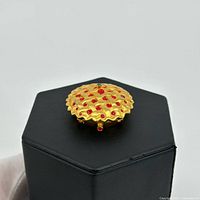 Top view showing gold lattice lid with red rhinestones and missing cherry