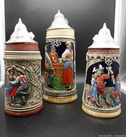 Front view of three ceramic beer steins with pewter lids