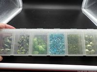 One organizer showing six compartments of assorted green and blue beads