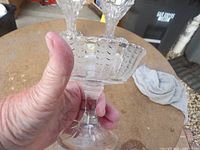 Side view of clear glass pedestal compote showing scalloped rim and paneled design
