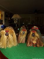 Three handcrafted wood troll figurines with straw beards and red berry eyes