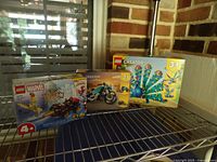 Three sealed LEGO sets on shelf: Marvel 10792, Creator 31135, Creator 31157 front boxes visible