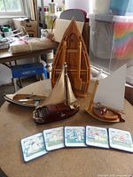 Group shot of three model boats, boat-shaped wall shelf, and five coasters