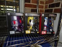All three boxed Transformers DZNR plush figures on shelf
