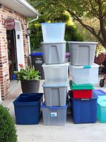 Stack of numerous plastic totes outside garage