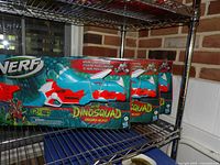 Front view of two sealed Nerf DinoSquad Tricera-Blast boxes on shelf