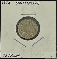 Reverse side of 1974 1/2 Franc coin showing denomination and date in holder
