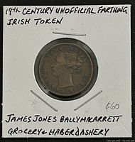Obverse of copper farthing token in holder with handwritten identification