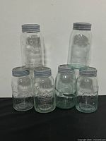 Group of six glass Crown mason jars with lids