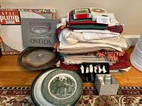 Overall lot with boxed platter and tray, stack of linens, serveware and accessories