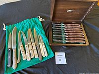 Lot overview showing Cutco box with steak knives and assorted knives on green pouch