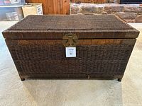 Front view of brown wicker trunk showing latch, handles, and overall condition