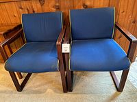 Front view of both armchairs showing upholstery color, piping, and overall design