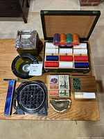 Full lot overview showing poker chip case, solitaire board with marbles, ashtrays and playing cards