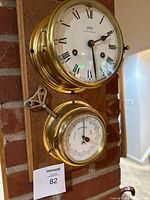 Front view showing clock above barometer on wood plaque