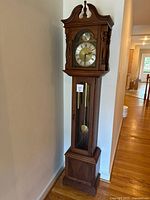 Full height view of wooden grandfather clock against wall