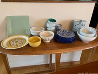 Full grouping of assorted ceramic bowls and plates on table