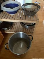 Overall lot showing silicone bowls and mesh strainer on shelf, stock pot below