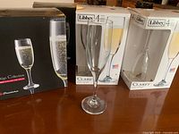 boxed Libbey Claret 4-packs and Pasabahce flute beside loose flute on table