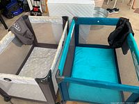 Top view of both play yards side by side showing colors, mesh sides, and included mattress