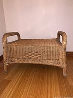 Front perspective of beige wicker ottoman showing overall structure
