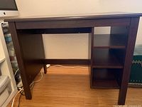 Front view of IKEA dark brown desk showing leg structure and shelving