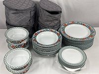 Full lot showing stacked dinnerware and four grey padded cases